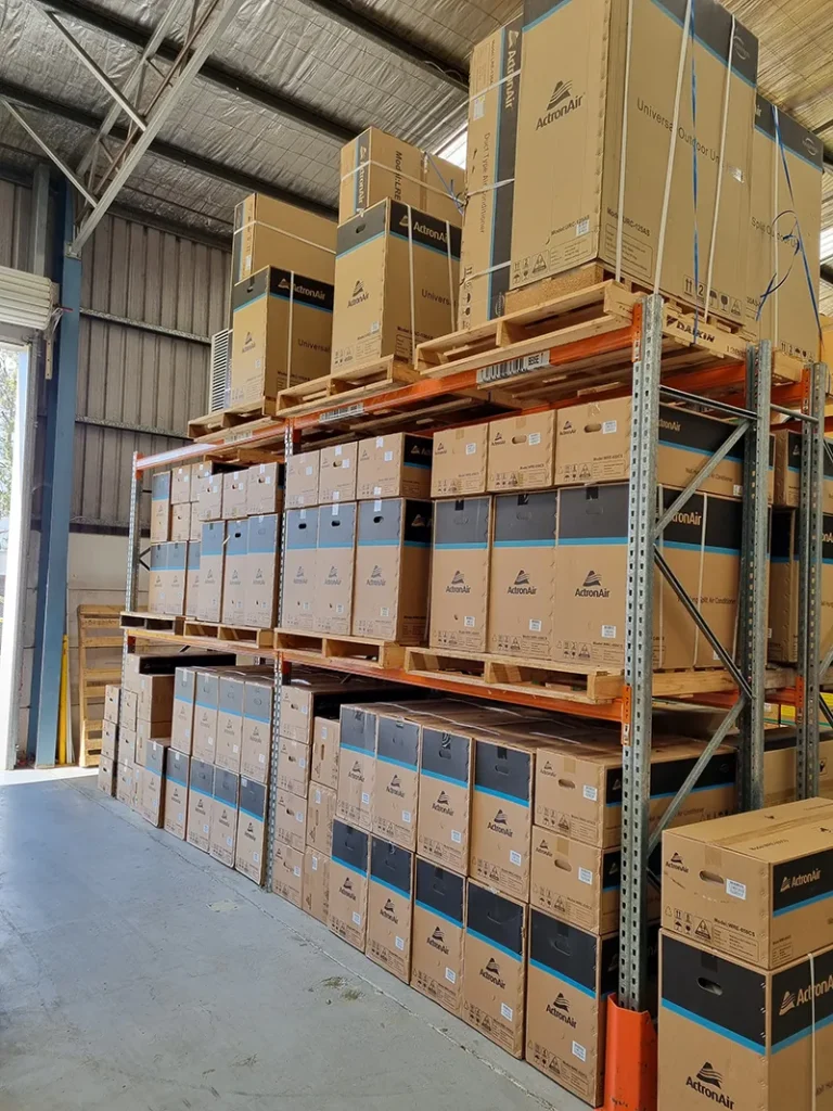 Multiple brands of air conditioning stock stacked on warehouse racking